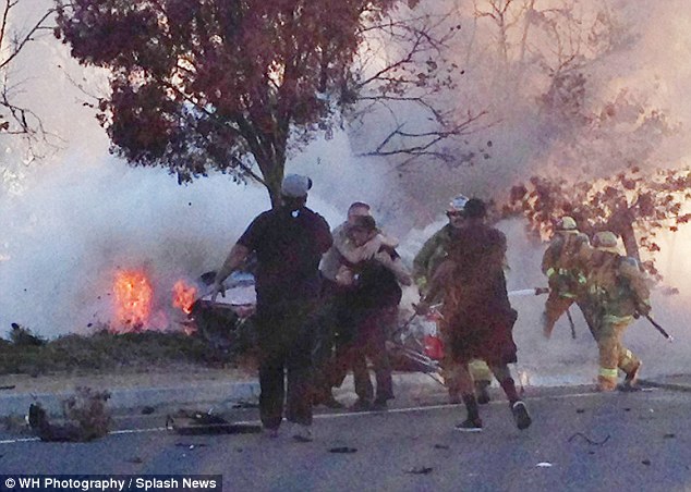 Tragic: This photo was taken just minutes after Walker's car crashed into a pole, and shows the Porsche in flames as fire marshals and police hold back friends who are trying to help 