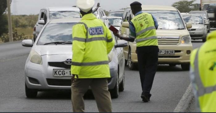 Police officers conduct a transport and road safety inspection of vehicles along a road.